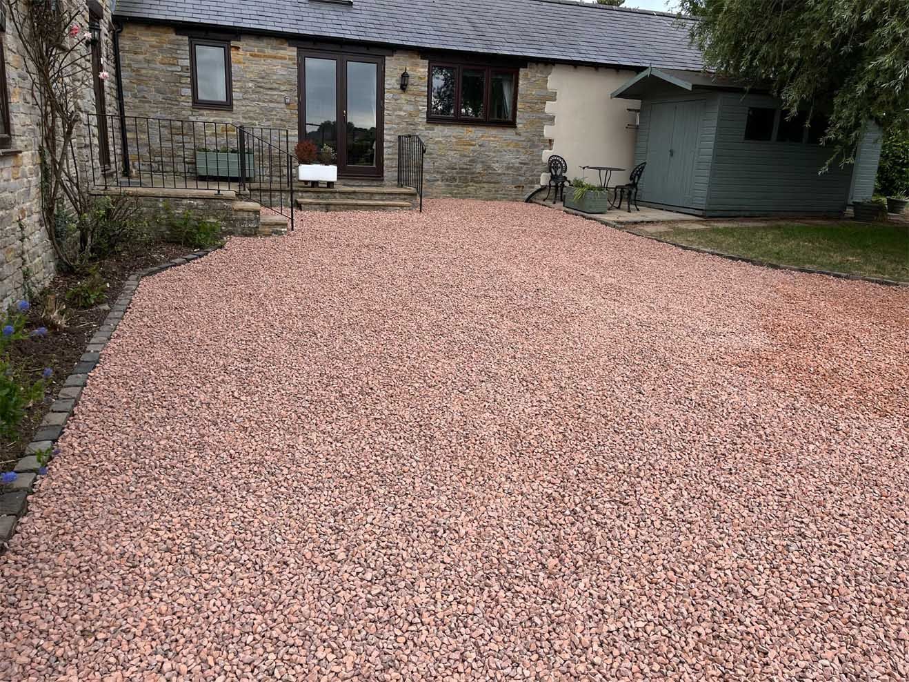 A gravel driveway infront of a house