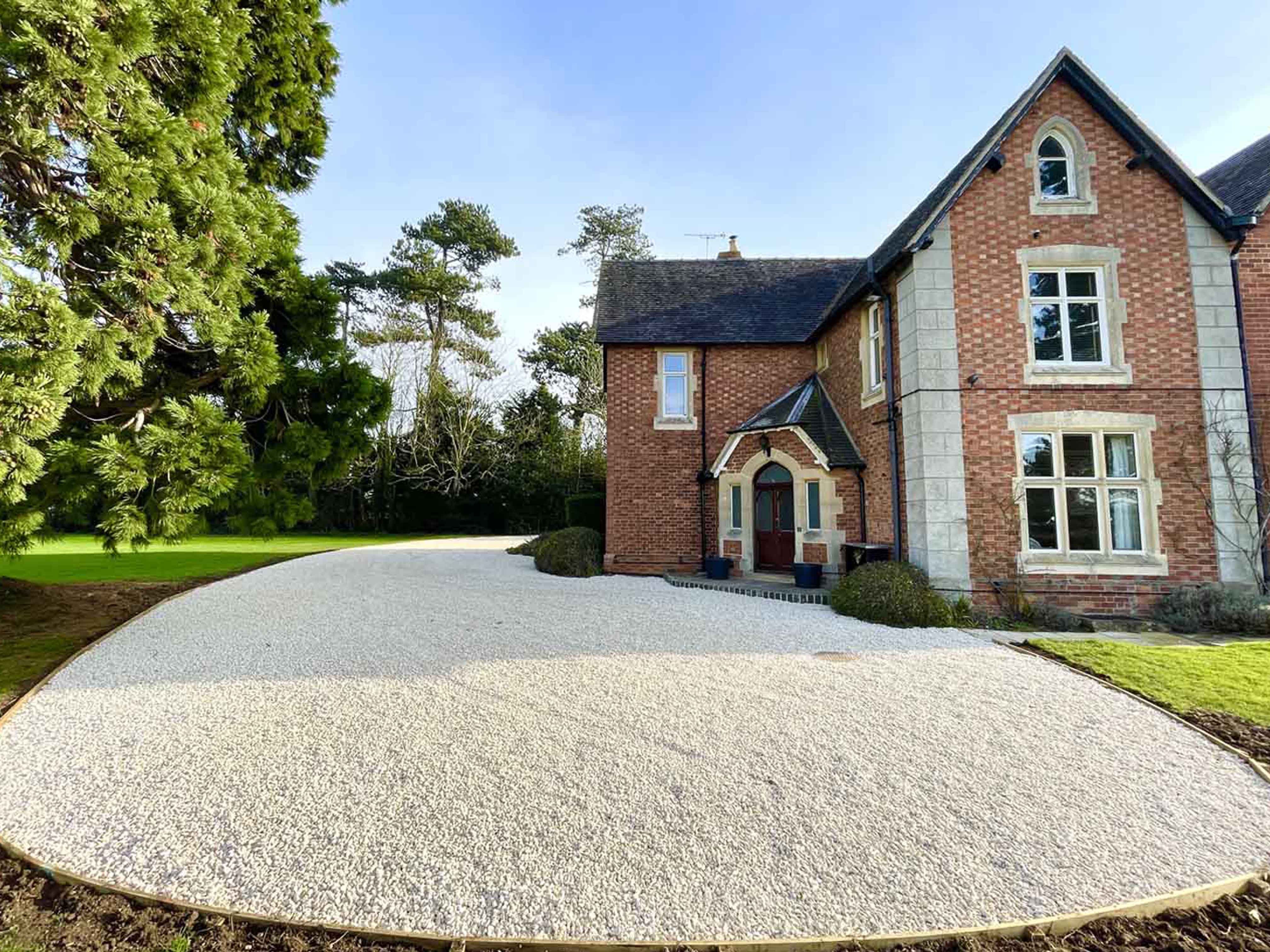 A beautiful white gravel driveway infront of a country house
